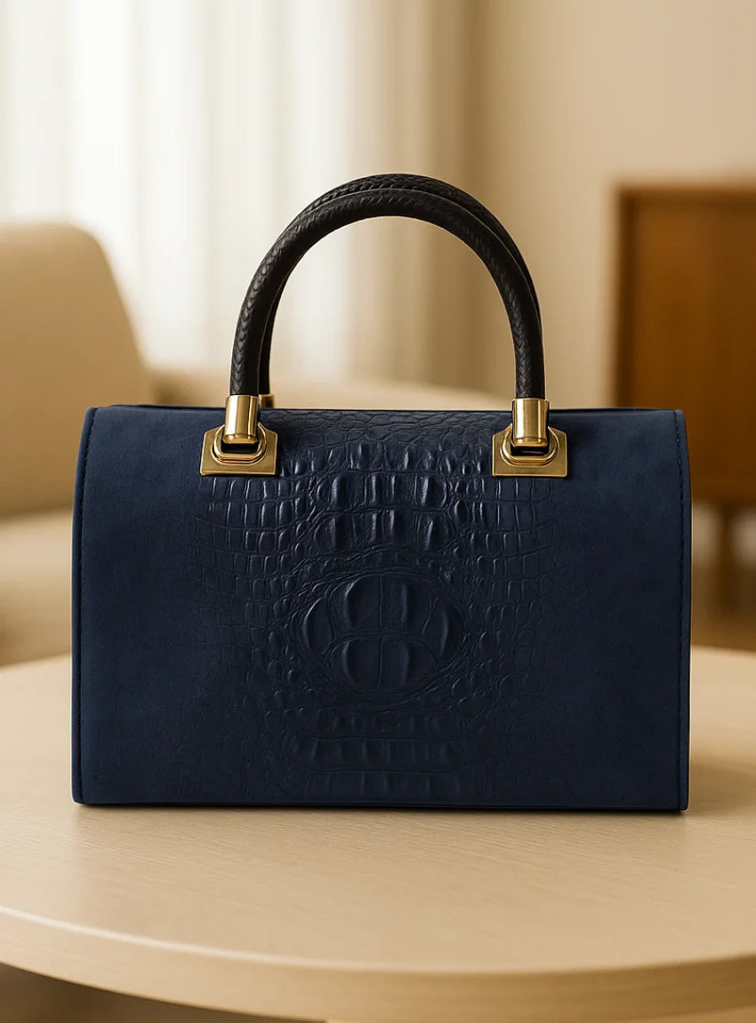Navy blue handbag with gold accents on a light wooden surface